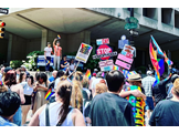 A large group of people hold signs and Pride flags at the Philadelphia Pride March.